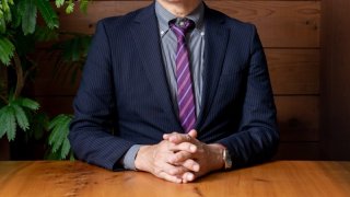 手を組むスーツの男性