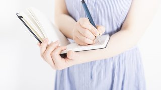 ノートにメモをとる女性