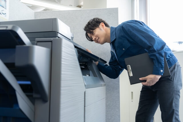 プリンターを覗く男性