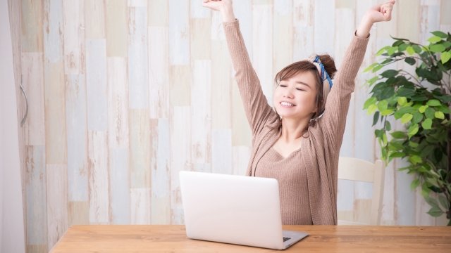 パソコンの前で伸びをする女性